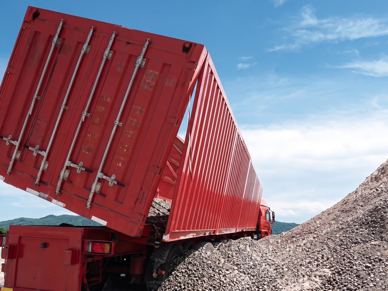 CYP9400L 60-Side Rollover Transport Semi-Trailer tipping to the side and discharging gravel, showing the rollover action