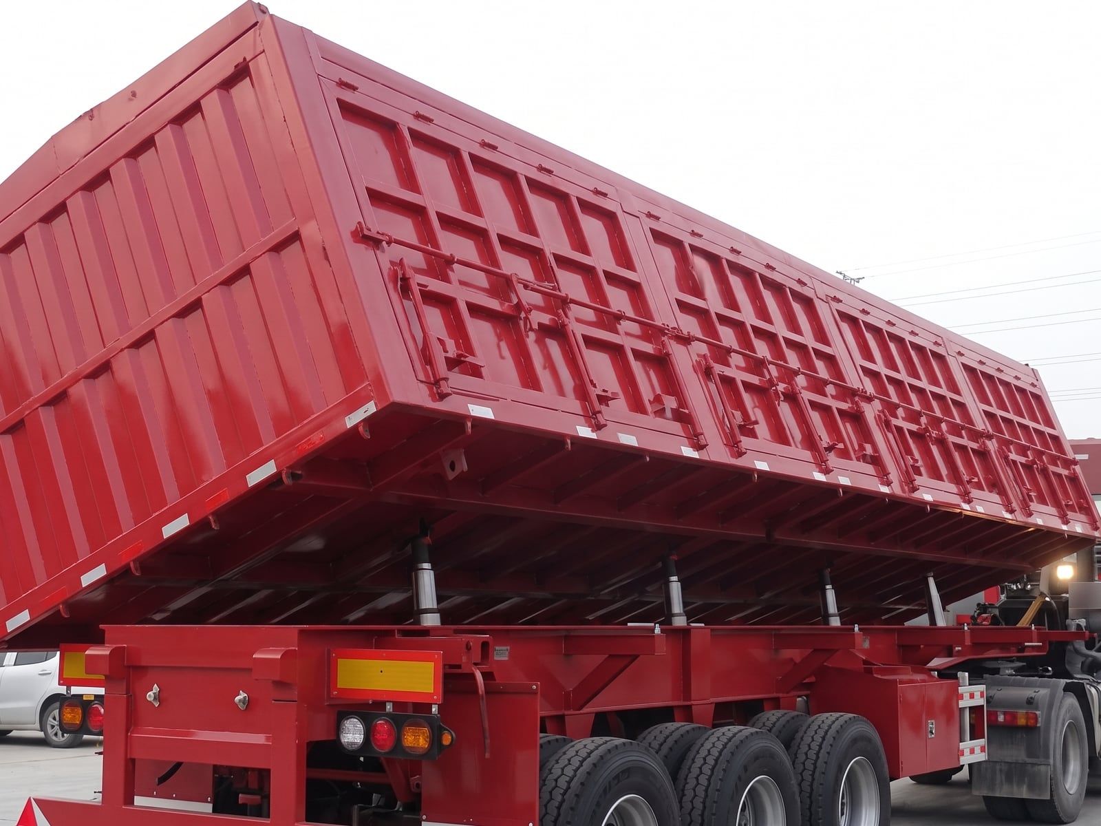 CYP9400L 60-Side Rollover Transport Semi-Trailer the red body seen from the rear three-quarter, tipped