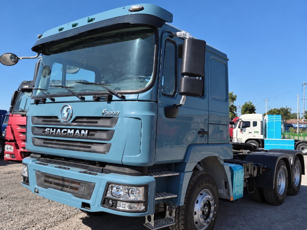 Shacman Delong F3000 6×4 Tractor Truck photographed three-quarter front, light blue Shacman cab, fifth wheel empty