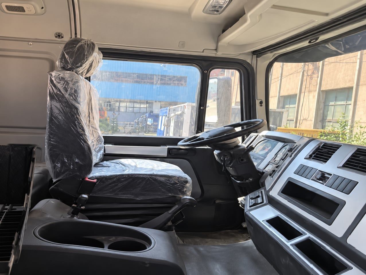 Shacman Delong F3000 6×4 Water Truck inside the cab: left-hand drive position, dashboard and seats still wrapped in delivery plastic