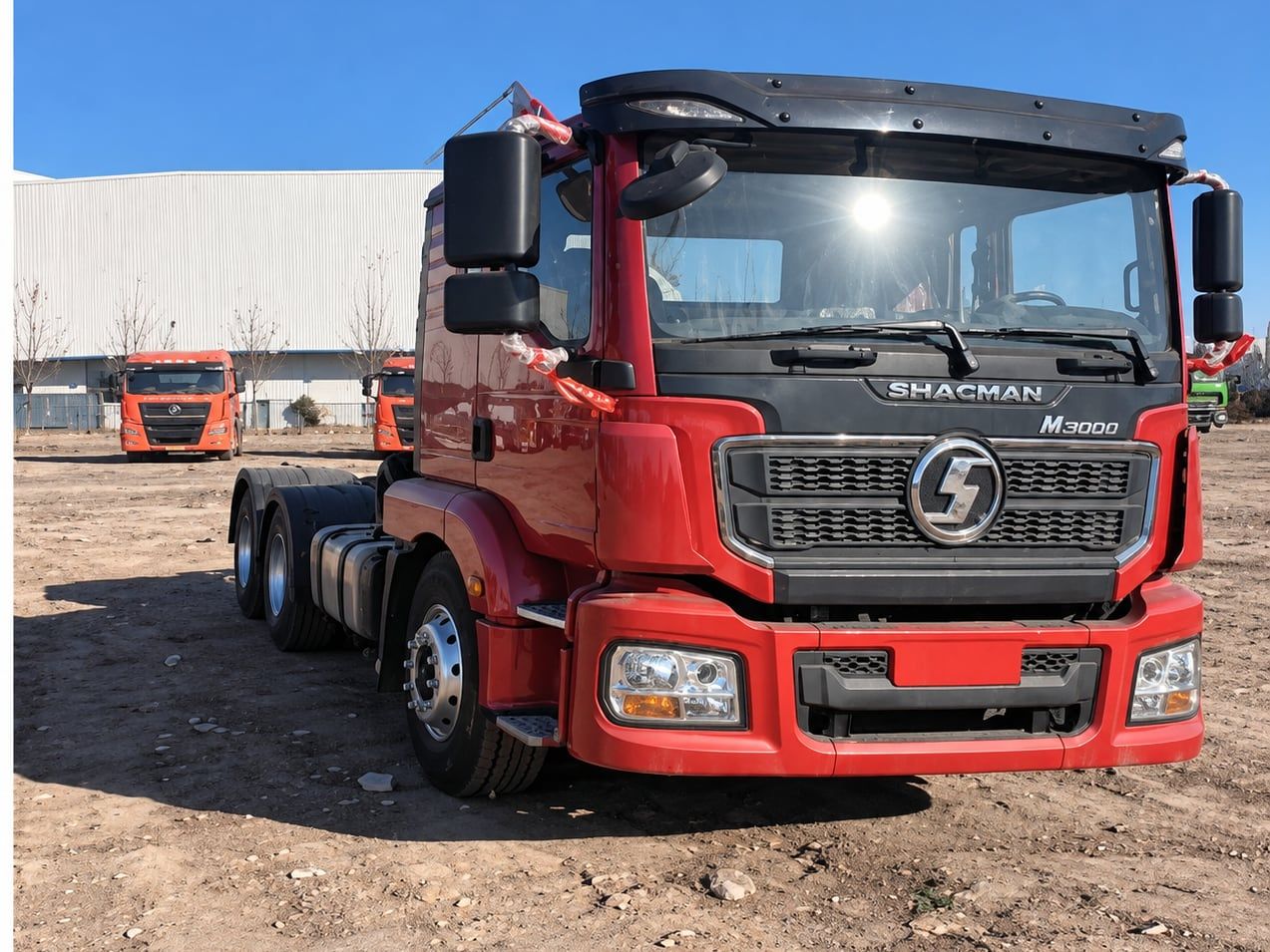 Shacman Delong M3000 6×4 Tractor Truck photographed front three-quarter in the yard, red cab, fifth wheel empty
