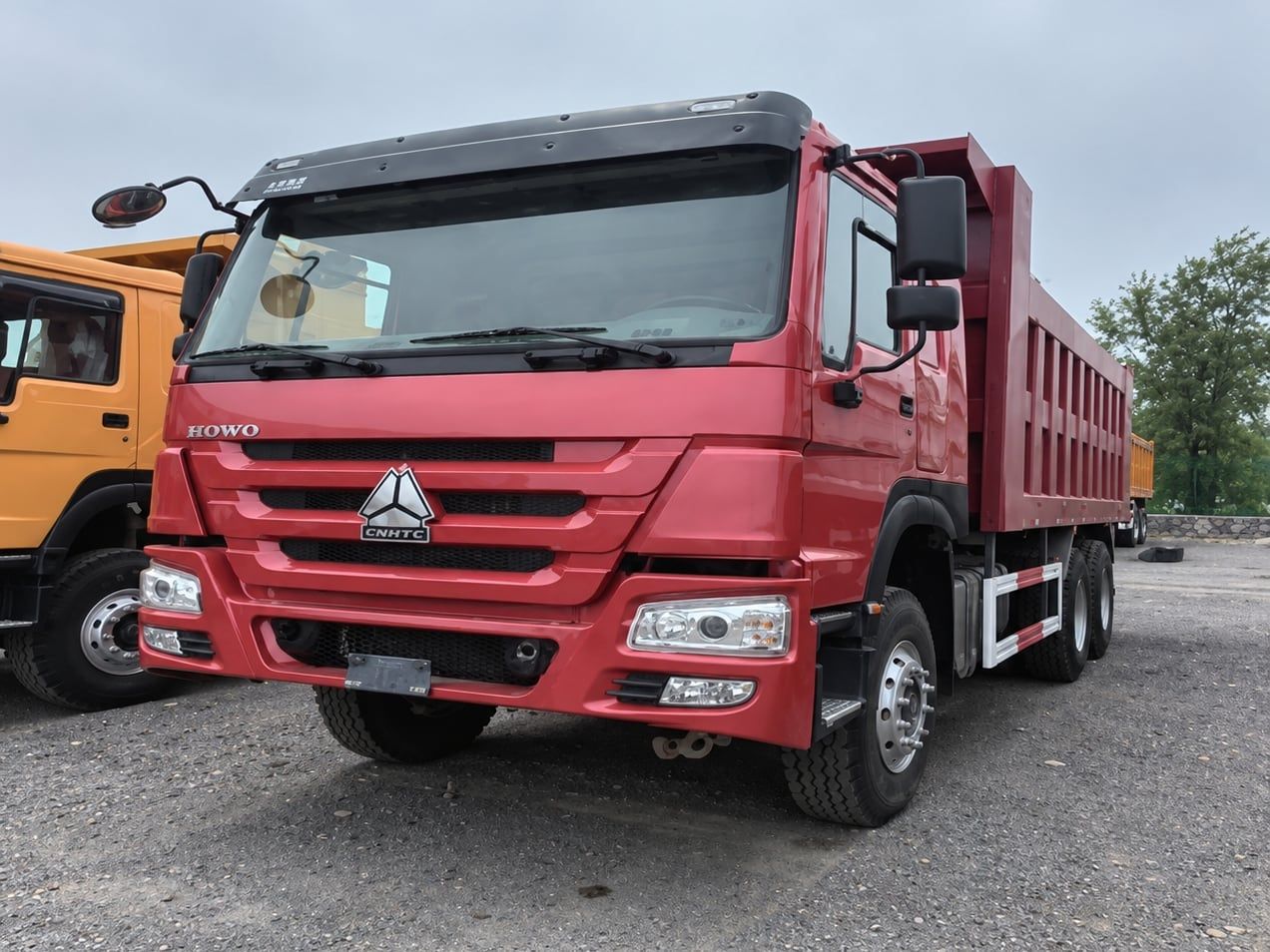 Sinotruk HOWO 6×4 Dump Truck photographed three-quarter front in the yard, red cab and red tipper body