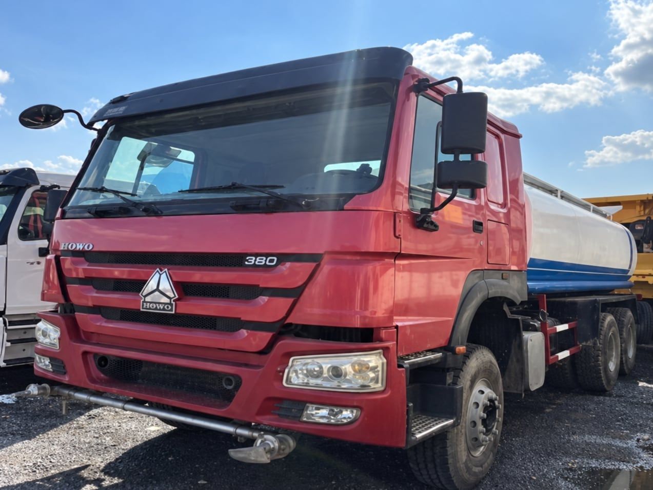 Sinotruk HOWO 6×4 Water Truck photographed three-quarter front in the yard, red cab and water tank behind