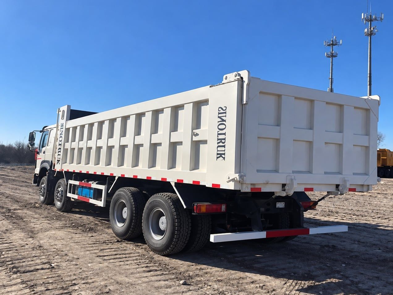 Sinotruk HOWO 8×4 Dump Truck seen from the rear three-quarter, showing the full length of the white tipper body and the four axles