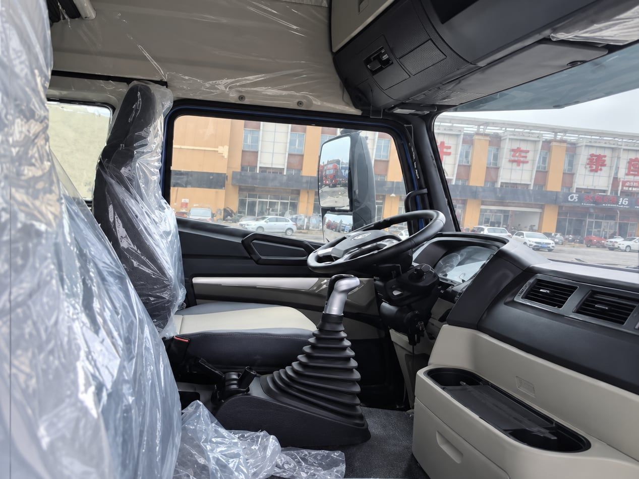 Sinotruk HOWO NX 6×4 Tractor Truck inside the cab: left-hand drive position, dashboard and gear lever, seats still in delivery wrapping