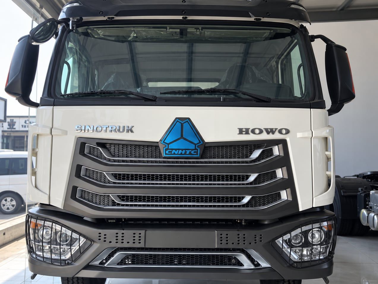 Sinotruk HOWO NX 6×4 Tractor Truck seen head-on under a canopy, showing the full width of the cab and the chassis