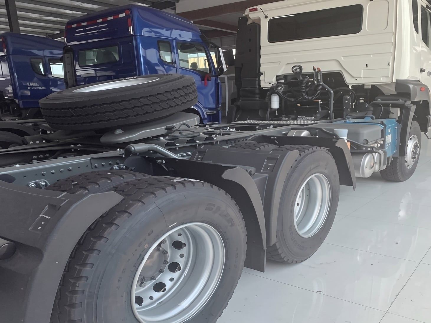 Sinotruk HOWO NX 6×4 Tractor Truck seen from the rear three-quarter in the yard, showing the chassis and the fifth wheel