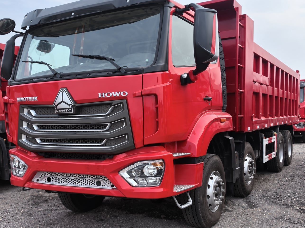 Sinotruk HOWO NX 8×4 Dump Truck photographed three-quarter front, red cab and red tipper body, four axles