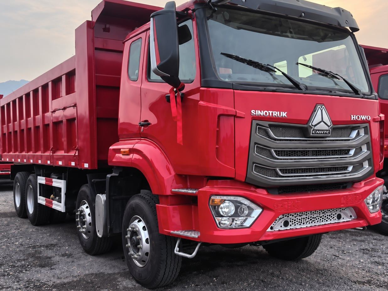 Sinotruk HOWO NX 8×4 Dump Truck photographed front three-quarter in the yard, red cab and tipper body